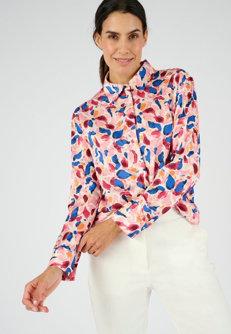 Camicia button-up rosa con un motivo di foglie astratte colorate nei toni del blu, rosso e viola, con maniche lunghe e colletto classico.