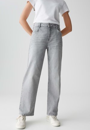 Graue Denim-Jeans mit hoher Taille, geradem Beinchnitt, dezentem Verblassen und fünf Taschen. Kombiniert mit weißen Sneakers und einem schlichten weißen T-Shirt.