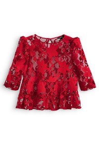 Haut en dentelle rouge avec motif floral, manches trois-quarts et ourlet volanté. Le matériau transparent permet de le superposer sur un débardeur ou une robe.
