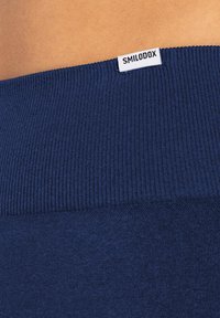 Granatowy materiał ribbed o gładkiej teksturze, z widoczną białą metką z napisem "SMILODOX" na pasku.