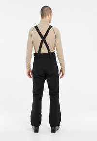 Pantalones de nieve negros con tirantes ajustables, que cuentan con una cintura alta y piernas ajustadas. Textura suave y dobladillos reforzados para mayor durabilidad.