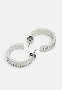 Sølv hoop øreringer med et glatt, avrundet design og en rad av klare krystaller langs frontkanten og post-back lukking.