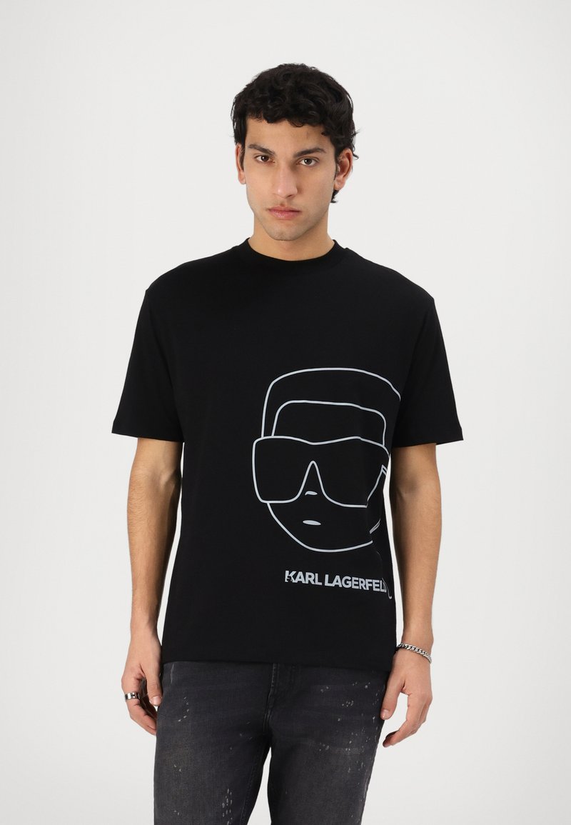 Black cotton t-shirt featuring a white outline graphic of sunglasses and a face, with "KARL LAGERFELD" printed beneath. Standard fit.