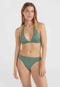 Zaļš bikini komplekts, kas sastāv no trīsstūrveida krūštura un vidējā seguma biksītēm, izgatavots no gludas auduma ar minimālām šuvēm un matētu virsmu.