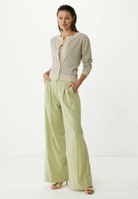 Beige och lavendelfärgad randig cardigan över en ljusgrön plisserad byxa, båda löst sittande. Har knappar och fickor, med strukturerad tyg.