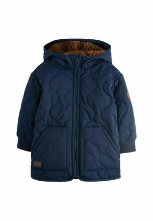 Marineblau gepolsterte Steppjacke mit Kapuze, ausgestattet mit braunem Kunstfellfutter, zwei Fronttaschen und gerippten Bündchen. Lederakzent am Saum.