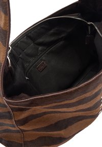 Brązowo-czarna torba z futerkiem w paski, zapinana na zamek. Wnętrze wyposażone w czarną podszewkę z kieszenią na zamek.