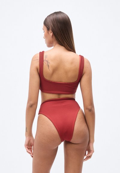 Μπικίνι μπορντό με ριμπ υφή, με κορυφή τύπου crop top με δομή και ψηλόμεσο κάτω μέρος. Ομαλή υφή και φαρδιές τιράντες, με μινιμαλιστικό σχεδιασμό.