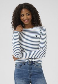Lange mouwen gestreepte shirt in wit en blauw, met een zwart hartembleem op de borst. Het materiaal lijkt zacht en aansluitend.