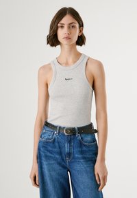 Graues Baumwoll-Top mit rundem Ausschnitt und ärmellosem Design, kombiniert mit blauen weiten Jeans und einem schwarzen Gürtel mit einer dekorativen Schnalle.