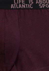 Bordowe bawełniane szorty z elastycznym czarnym pasem z różowym napisem. Gładka struktura, boczne kieszenie i luźny krój.