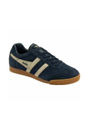 Sneakers en suède bleu marine avec des rayures beiges, dotés d'une semelle en caoutchouc et d'accents texturés. Lacets maintenus par six œillets.