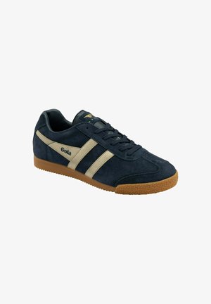 Zapatillas de ante azul marino con rayas beige, que cuentan con una suela de goma y acentos texturizados. Cordones asegurados a través de seis ojales.
