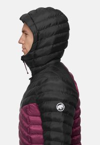 Czarna i bordowa ocieplana kurtka o puszystym fasonie. Posiada dopasowaną kieszeń na kaptur i logo na lewym ramieniu. Teksturowany, lekki materiał.