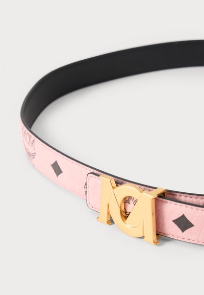 Ceinture en cuir rose avec motifs losanges noirs et boucle double M dorée sur fond uni.