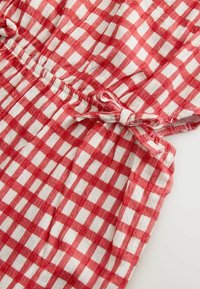 Rødt og hvidt ternet stof med elastisk taljebånd og knyttet sløjfedetalje på letvægtsbeklædning.