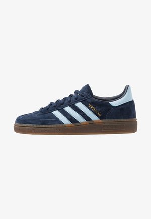 Tumesinine sametist Adidas tennis, helesiniste triipudega, kummist tallaga, helesinise kandetabiga ja kuldse "Spezial" brändimisega küljel.