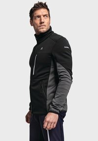 Schwarz-graue Fleecejacke mit halbem Reißverschluss und hohem Kragen, mit reißverschlussgesäßter Brusttasche, seitlichen Taschen und kontrastierenden Ärmel-Panels.