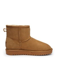 Brown suede ankle boot with fur lining, loop pull tab at back, stitched detailing, and flat rubber sole with ridged tread.