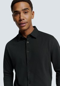 Zwarte lange mouwen knoopshirt met een kraag, met een gladde textuur en zwarte knopen. De pasvorm is modern en getailleerd.