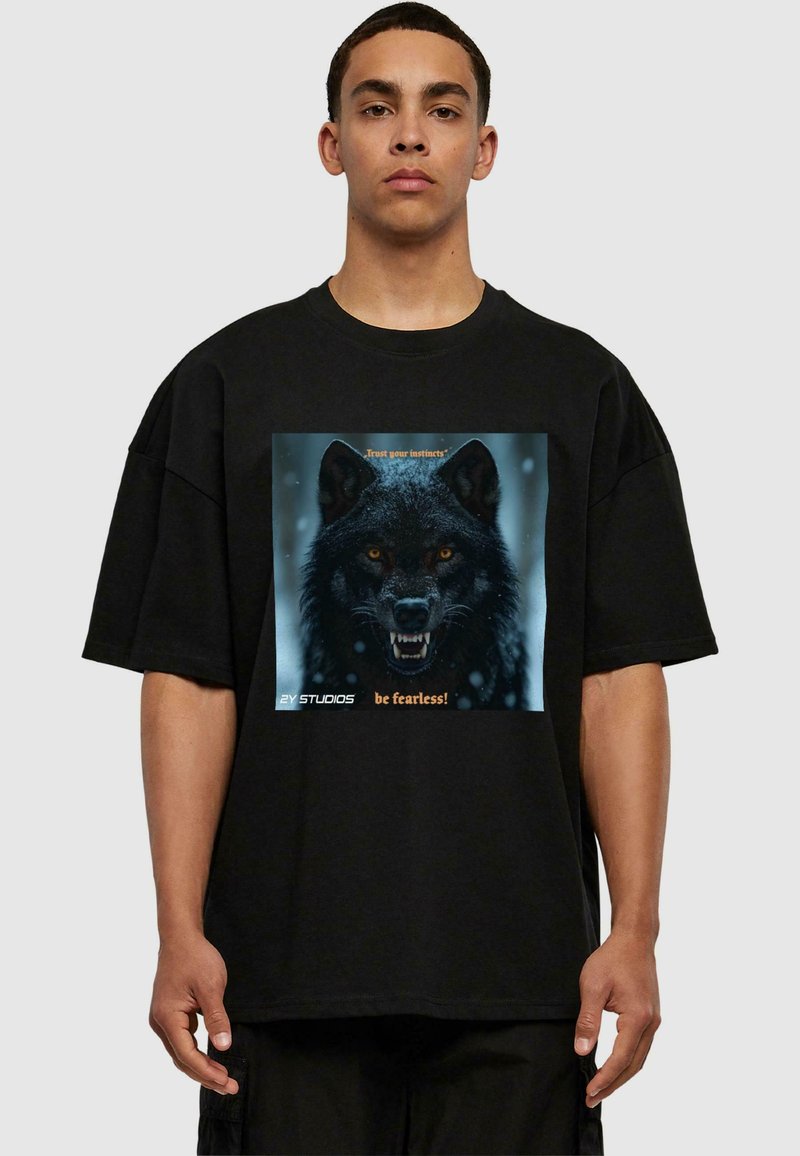 Black oversized t-shirt featuring a graphic of a fierce wolf's face with yellow eyes, text "Trust your instincts" and "be fearless!" in orange.