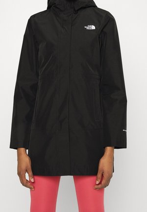 Veste noire imperméable à capuche avec poches avant et logo The North Face sur la poitrine, portée avec des leggings roses.