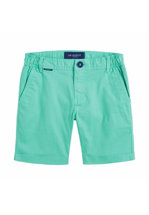 Shorts en coton vert clair avec une taille élastique, un détail de bouton, des poches avant et une couture discrète. Étiquette de la marque visible sur la taille.
