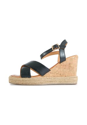 Wedge sandal with cork heel, braided rope platform, black crossed leather straps, and ankle strap with gold buckle.