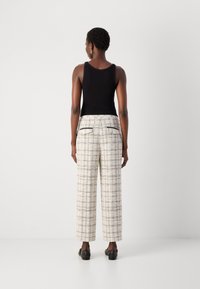 Top a fascia nera a costine abbinato a pantaloni a gamba larga a vita alta in un pattern a quadri crema con accenti neri e tasche posteriori.