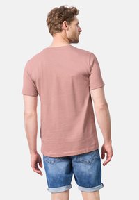 T-shirt a girocollo rosa chiaro realizzata in cotone, con maniche corte e vestibilità rilassata, abbinata a pantaloni corti in denim con risvolti.