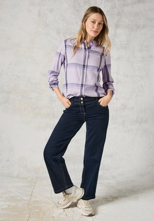 Lyslilla ternet knap skjorte med lange ærmer, parret med mørkeblå vide jeans og beige sneakers. Enkel design og afslappet pasform.