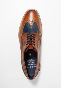 Scarpe eleganti in pelle marrone con un pannello testurizzato blu scuro, design wingtip, punta rotonda e lacci neri. Presentano forature decorative.