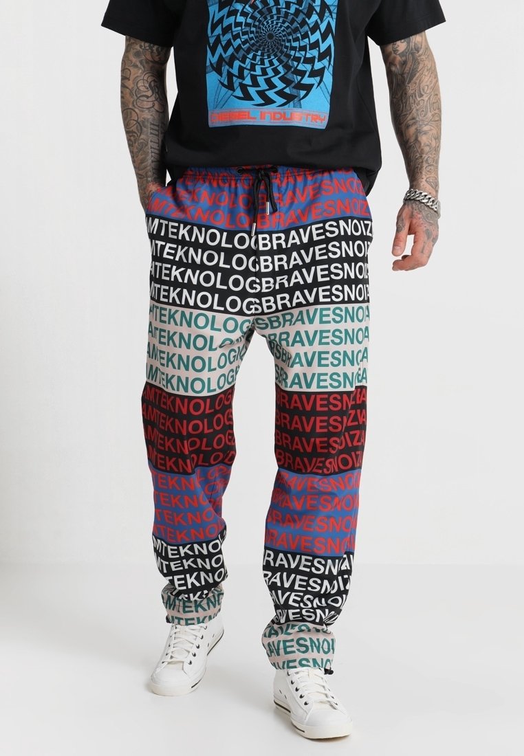Mehrfarbige Jogginghosen mit auffälligen Textmustern in Rot, Grün, Blau und Schwarz. Aus leichtem Stoff mit einem elastischen Bund gefertigt.