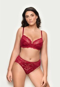 Punainen pitsinen rintaliivisetti ja korkeavyötäröiset alushousut, joissa on kukkakuvioita, hienovarainen kiilto ja säädettävät hihnat neutraalilla taustalla.