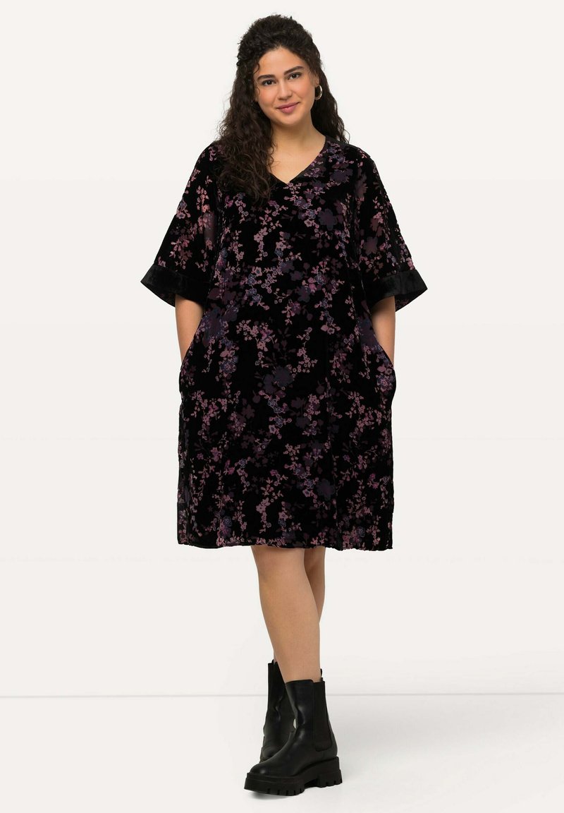 Mustikka samettimekko, jossa on purplekukkakuvio, V-aukko, lyhyet kellohihat ja sivutaskut. Yhdistetty mustiin nilkkureihin.