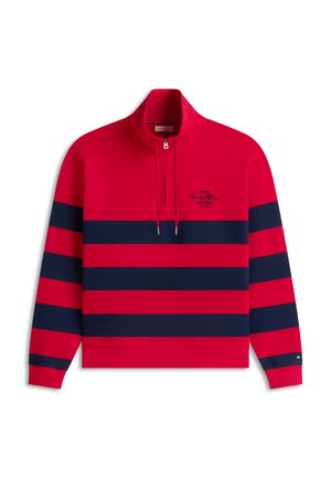 Rød pullover med lange ærmer med marineblå vandrette striber, kvart lynlås krave og lille skriftslogo på venstre bryst.