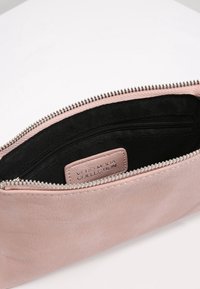 Růžová umělá kožená taštička s černým interiérem, stříbrným zipem a štítkem s nápisem "VERO MODA COLLECTION" uvnitř.