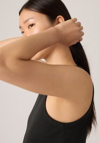 Svart ribbestrikket tanktopp med scoop hals og brede armhull, som fremhever en glatt tekstur og en figurnær design.