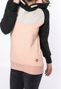 Sudadera con capucha que presenta bloques de color en gris oscuro, gris claro y rosa pastel. Incluye un pequeño diseño de corazón en la parte inferior izquierda.