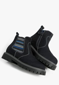 Bottes en daim noir avec panneaux latéraux élastiques présentant des rayures bleues et grises. Semelles épaisses en caoutchouc noir et détails de couture contrastants blancs.