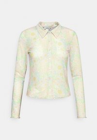 Camisa de manga longa de botões em cores pastel suaves com padrões florais. Apresenta um colarinho pontudo e botões rosa. Tecido suave e leve.