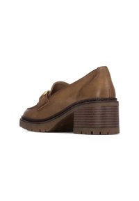 Zapato de tacón de cuero marrón con puntera redondeada, un pequeño detalle en dorado y un tacón en bloque texturizado con rayas. Suela con estrías para mayor tracción.