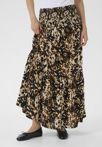 Leopard print maxi skirt made of soft fabric, featuring a smocked waistband, tiered design, and flowing silhouette. Black ballet flats worn.
