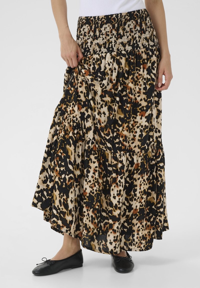 Leopard print maxi skirt made of soft fabric, featuring a smocked waistband, tiered design, and flowing silhouette. Black ballet flats worn.