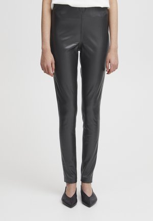 Leggings en simili cuir noir avec une texture lisse, fit slim, taille haute et sans coutures visibles. Associés à des ballerines noires à bouts pointus.