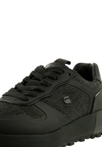 Svart sneakers med ett texturerat tygöverdrag, syntetiska overlay, tjock gummisula, rund tå och integrerat snörningssystem.