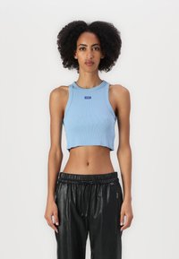 Lichtblauw geribd crop tanktop met een ronde halslijn en logopatch, gecombineerd met zwarte broek met koord in een gladde, glanzende textuur.