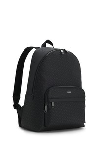 Sac à dos noir avec une texture lisse, une forme arrondie, un petit logo discret et une poche frontale zippée avec double tirette.