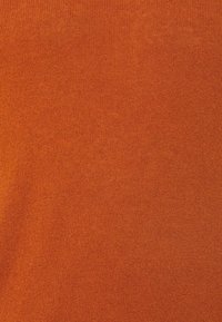 Närbild av texturerad orange stickad tyg med ett fint, enhetligt vävmönster.