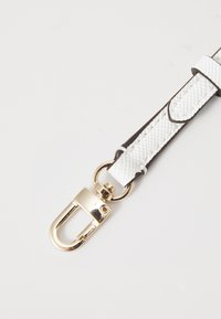 Cinturino in ecopelle bianca con texture a diamante e dettagli marrone scuro, dotato di una chiusura in metallo dorato con un attacco circolare.